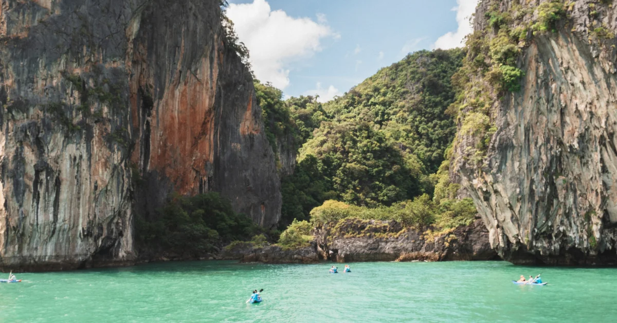 Kayaker entering the dark entrance of Ice Cream Cave on Panak Island, Phang Nga Bay